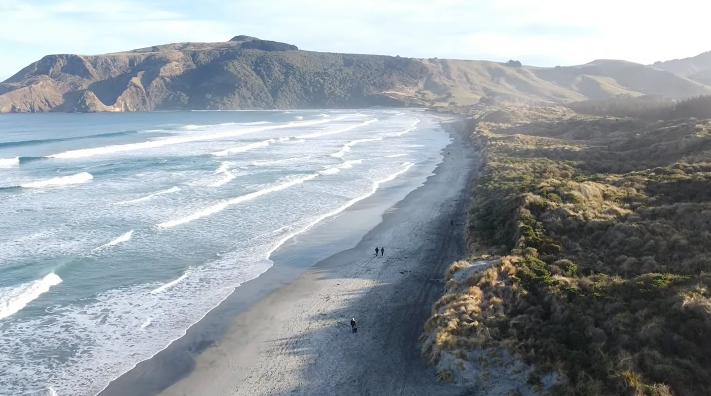 A few walkers strung along the empty sand at first light, the kind of quiet that makes the long peninsula drive worth it, All