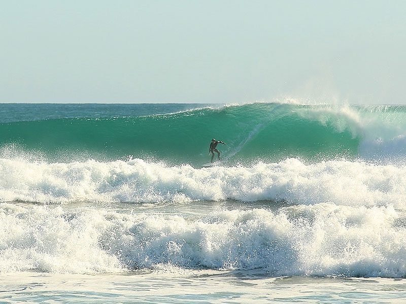 A surfer finding a clean wall on a Baylys peak, Baylys Beach surf spot, Northland West, New Zealand.