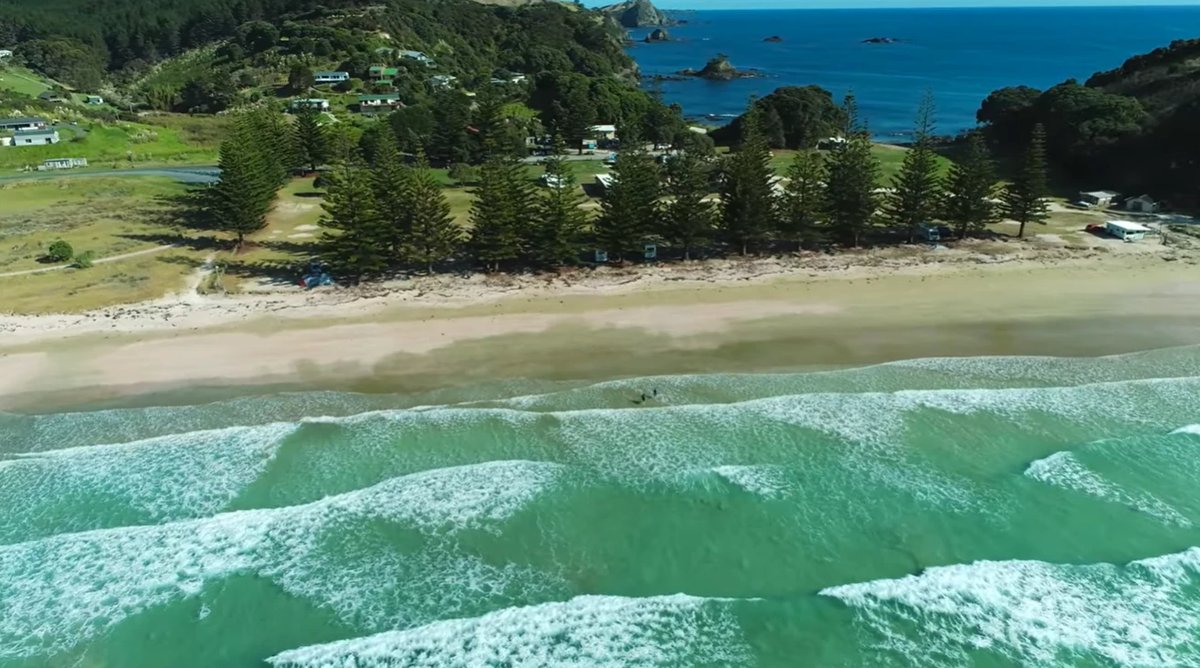 The village backed by green hills and the islands offshore, Matauri Bay surf spot, Northland East, New Zealand.