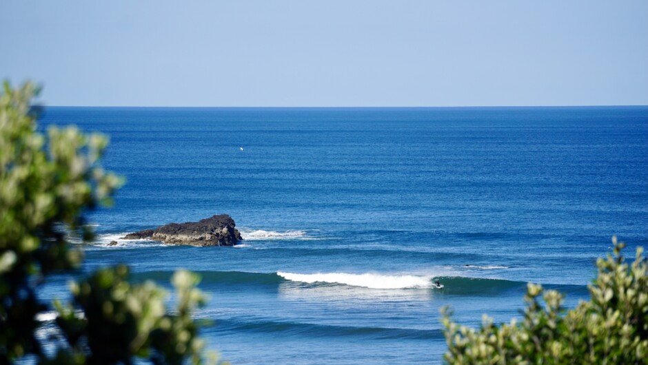 A peak with the rock in the lineup. Several banks work across the bay on the right swell, Maukātia Bay surf spot, Auckland We