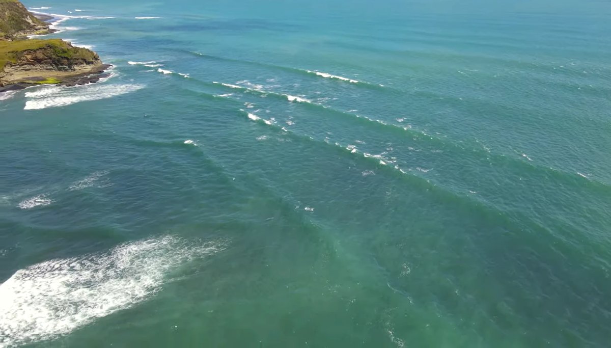 Lines of swell wrap in toward the cliffs, fanning out into the clean sets that show up when it is on, Mōkau surf spot, Tarana