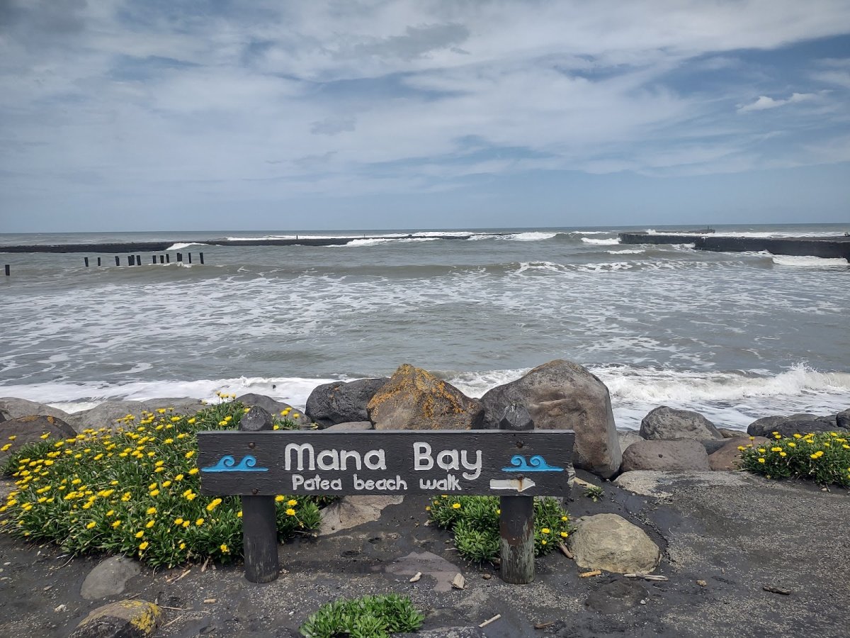 Mana Bay, Pātea's black-sand surf beach, with the old breakwaters and surf behind, Pātea surf spot, Taranaki / SH45, New Zeal