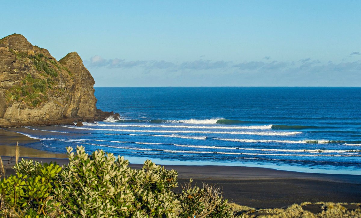 South Piha lefts peeling under the Camel Rock headland on a clean light-wind morning, Piha surf spot, Auckland West, New Zeal