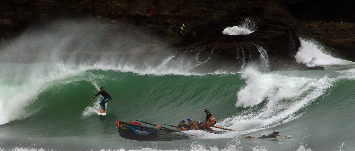 Wave and surf lifesaving IRB in the same frame. Two surf clubs patrol the beach in summer, Piha surf spot, Auckland West, New