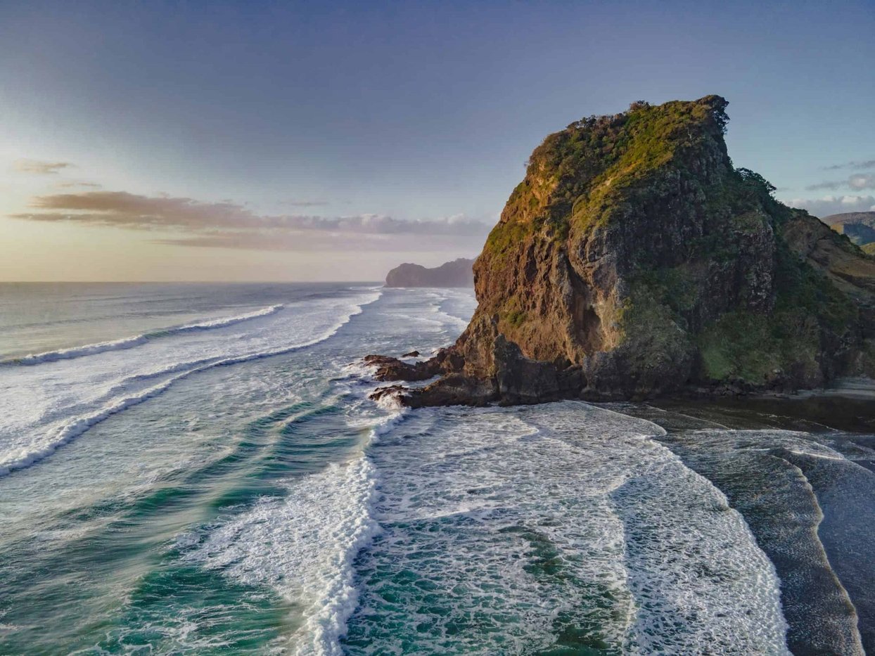 Lion Rock at golden hour. The south side back-wash that makes peaks here heavier than they look, Piha surf spot, Auckland Wes