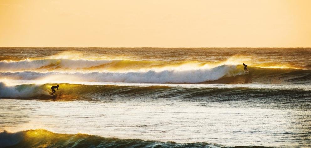 Golden hour at Manu. Two surfers, one lined-up set, the kind of evening Raglan is known for, Raglan Waikeri / Manu surf spot,