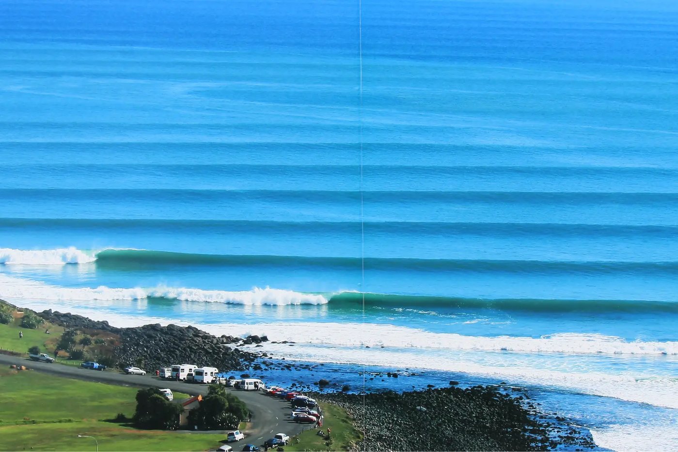 Manu Bay on a clean day. The world-famous lined-up left-hand point peeling for 300+ metres past the carpark, with the vans, s