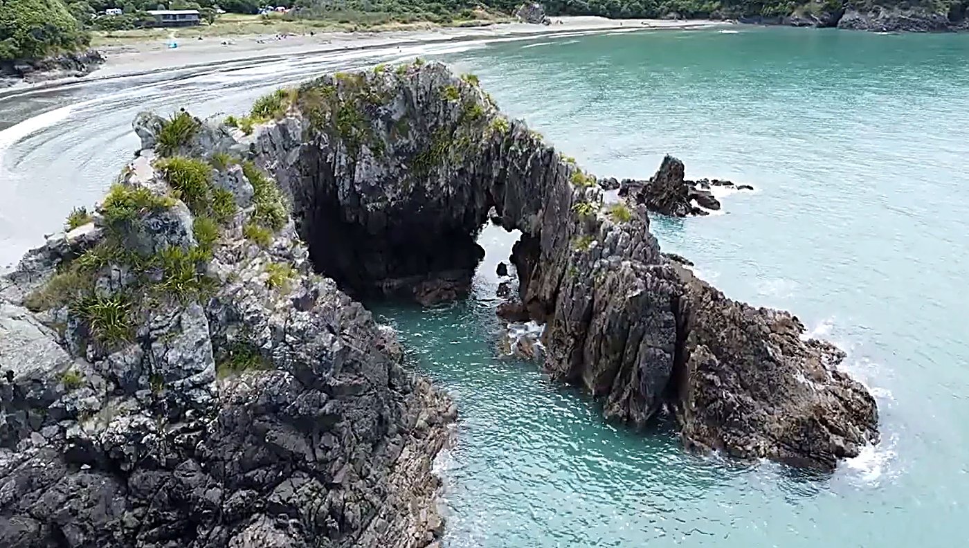The bay's landmark sea arch stands off the sand, the campground and beach tucked in behind on the edge of the Marlborough Sou