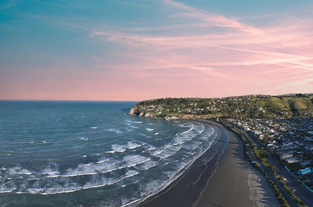 Dusk settling pink over Sumner beach as small lines peel down the sand toward the sheltered Scarborough corner, Sumner / Scar