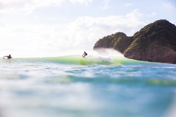 A clean Bethells morning, surfer in the pocket with the green Waitākere headland behind, Te Henga / Bethells surf spot, Auckl